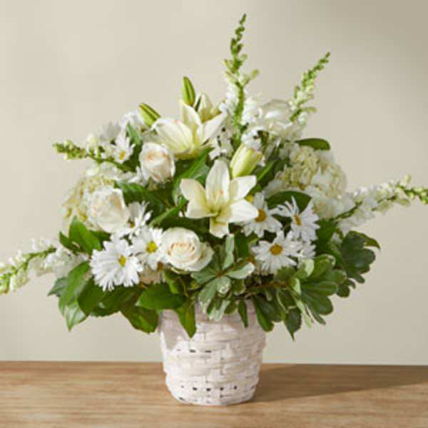 White lilies and daisies arranged in a white basket