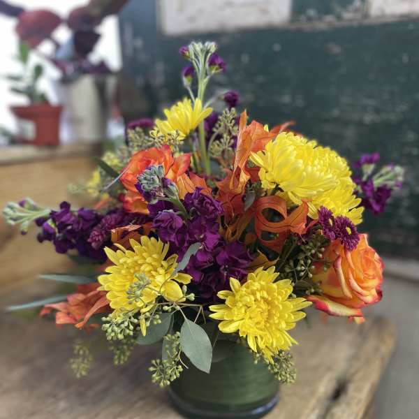 Bouquet of yellow chrysanthemums and orange roses in a green vase