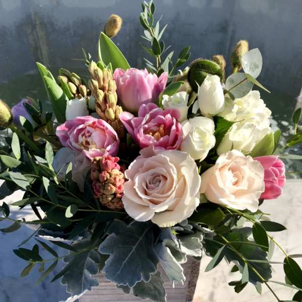 Low arrangement of blush roses and pink tulips in a whitewashed wooden box