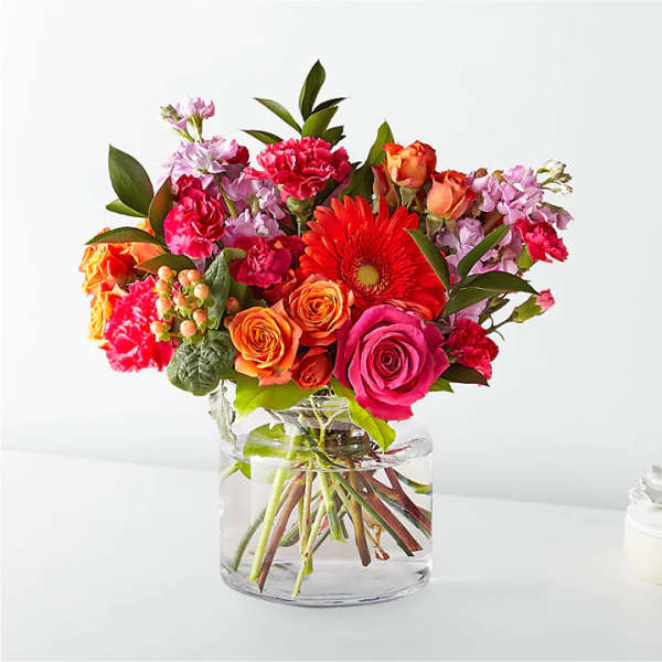 Mixed bouquet of roses, gerbera daisies, and carnations in a clear glass vase