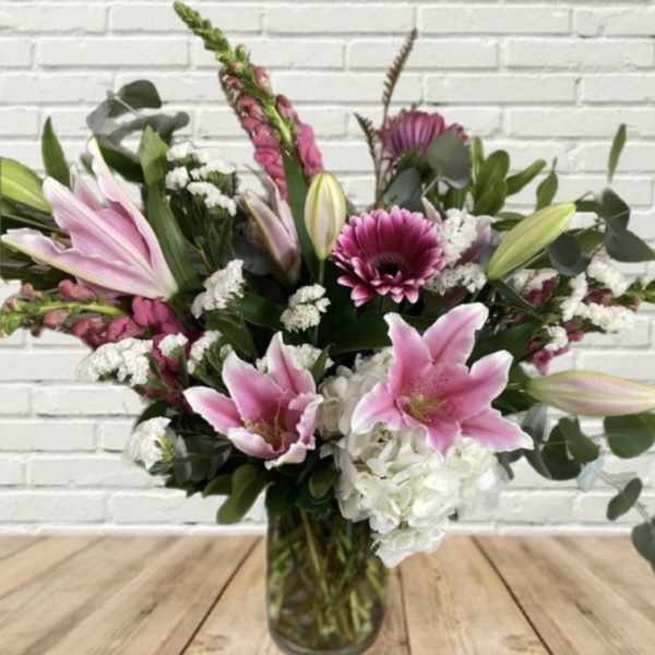Pink lilies and mixed flowers arranged in a glass vase