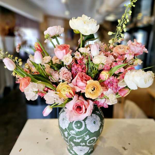 Mixed pink, white, and yellow flowers arranged in a patterned vase
