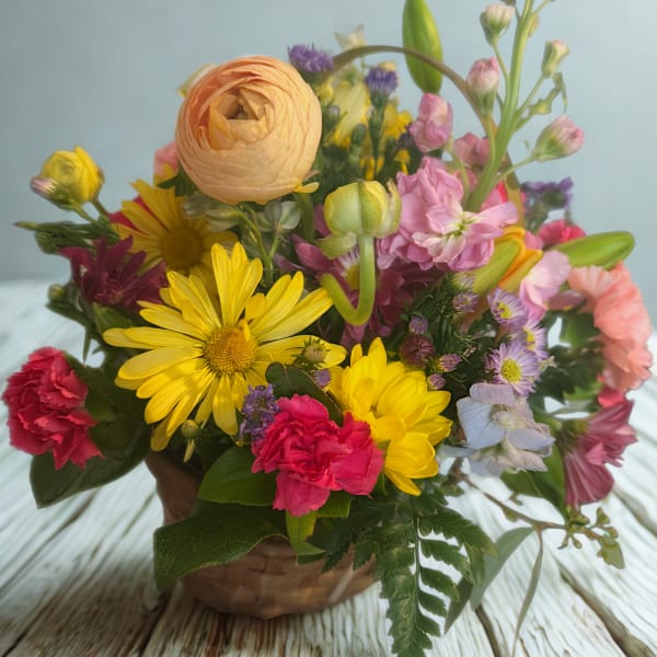 Mixed bouquet of yellow, pink, and peach flowers in a basket