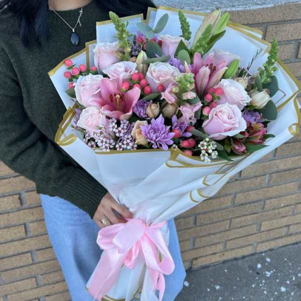 Large bouquet of pink roses, lilies, and purple flowers wrapped in white paper