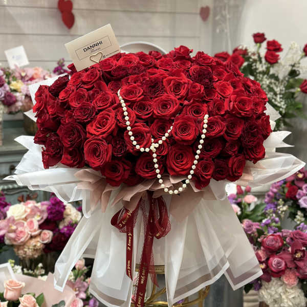 Large bouquet of red roses with pearl strands and white wrapping