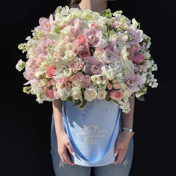 Large pastel bouquet of roses, orchids, and white blooms in a blue hatbox