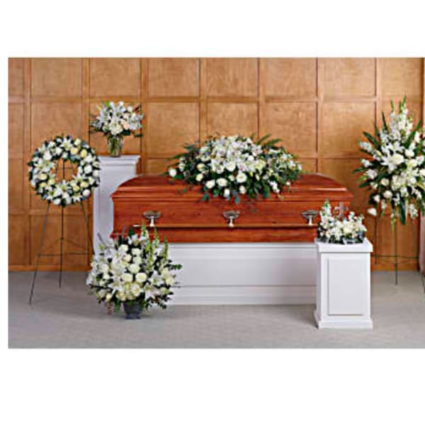 Funeral casket surrounded by white floral sprays and wreaths
