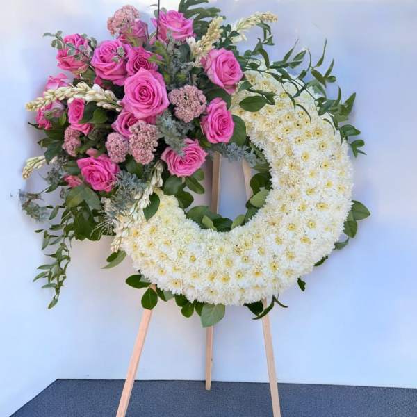 Heart-shaped floral wreath with pink roses and white chrysanthemums on an easel