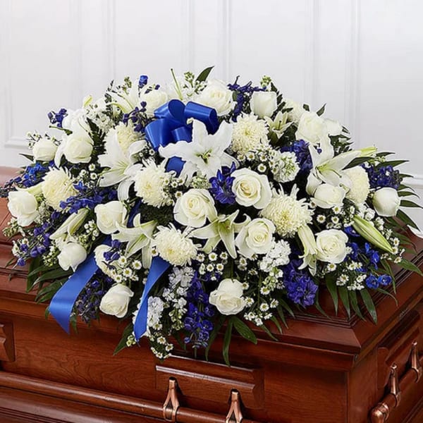 White and blue funeral spray on a casket with ribbon