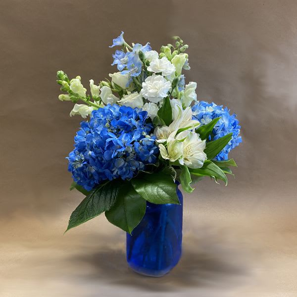 Blue and white flower arrangement in a cobalt glass vase