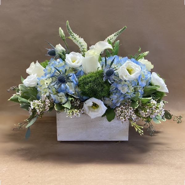 Blue and white floral arrangement in a white rectangular container