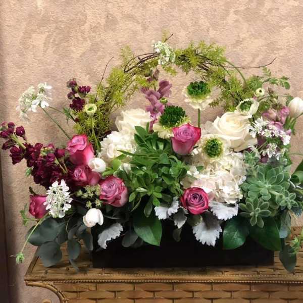 Mixed floral arrangement with pink and white roses in a low black container