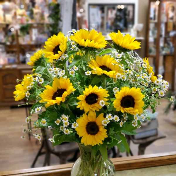 Bouquet of yellow sunflowers and small white daisies in a clear glass vase