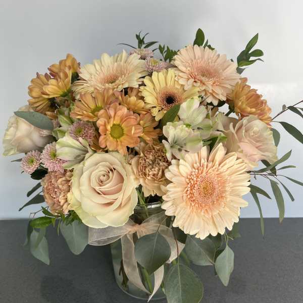 Peach and cream bouquet with roses, gerbera daisies, and chrysanthemums in a glass vase