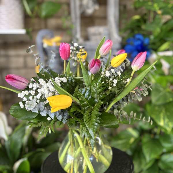 Bouquet of pink and yellow tulips in a clear glass vase