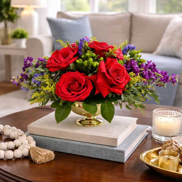 Red roses in a gold vase with purple filler flowers
