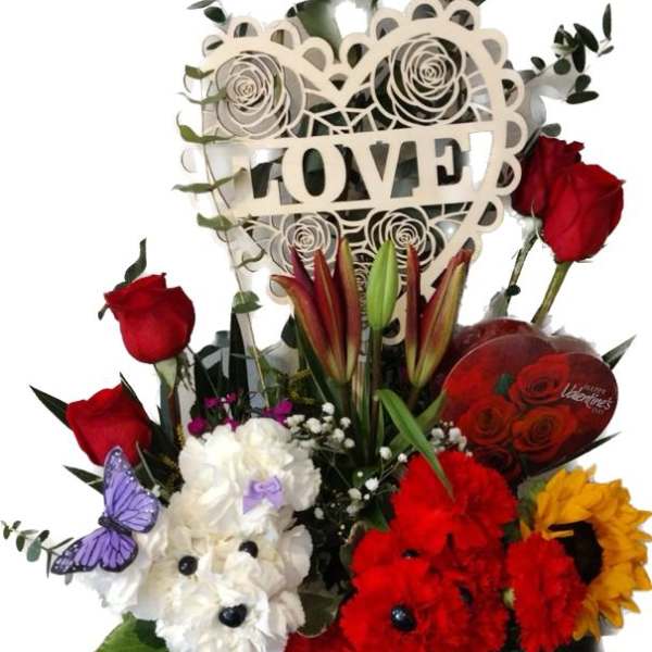 Red roses and mixed flowers arranged around a decorative LOVE sign