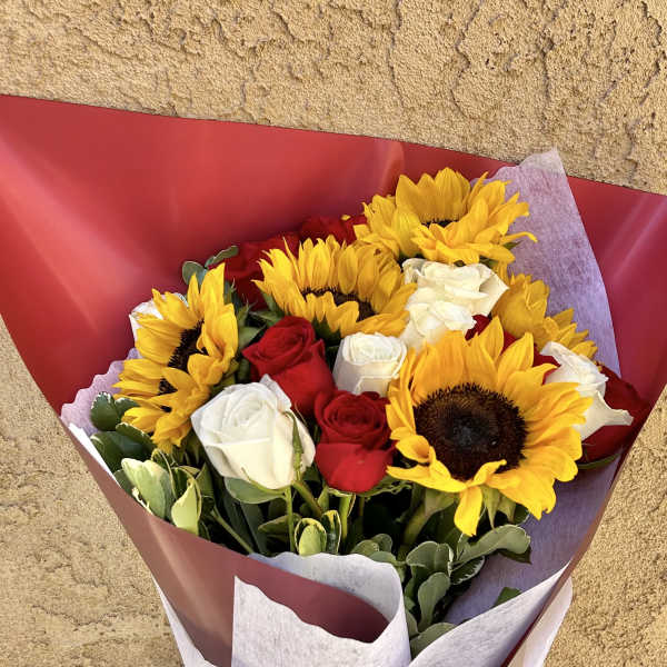Bouquet of yellow sunflowers and red and white roses wrapped in red paper