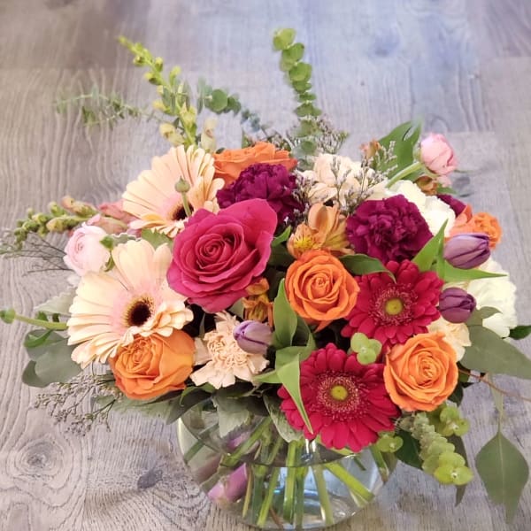 Mixed bouquet of roses, gerbera daisies, and carnations in a glass vase