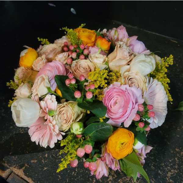 Bouquet of pink, cream, and yellow flowers with berry accents
