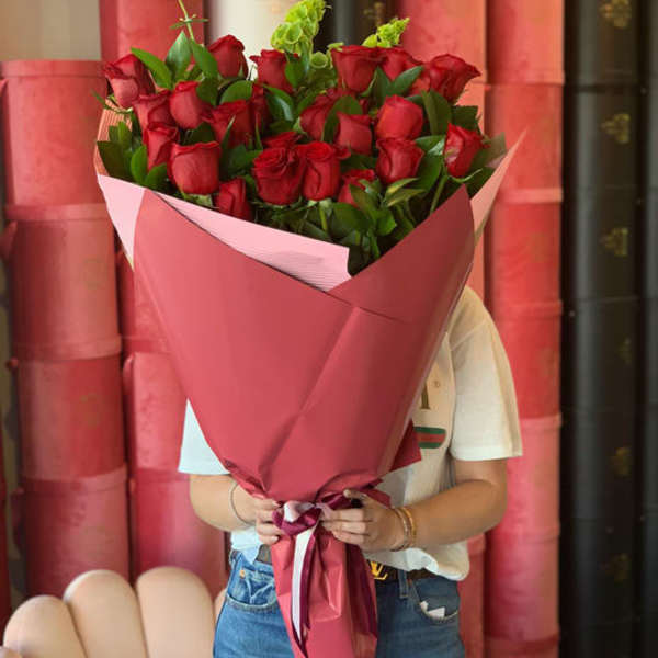 Large bouquet of red roses wrapped in pink paper