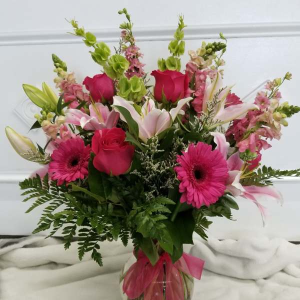 Pink and white mixed bouquet in a glass vase with a pink ribbon