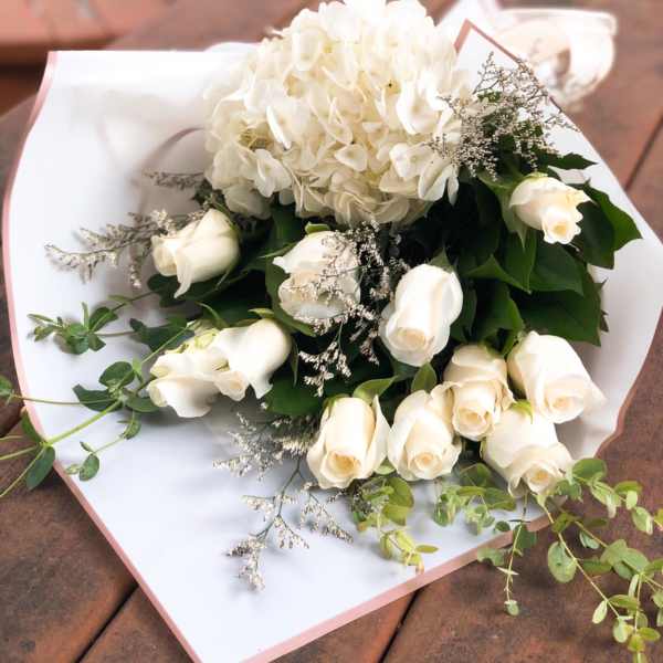 White roses and a white hydrangea bouquet wrapped in white paper