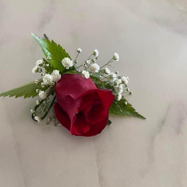 Red rose boutonniere with baby's breath and green leaves