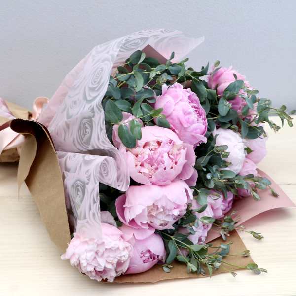 Bouquet of pink peonies wrapped in kraft paper and pink patterned cellophane