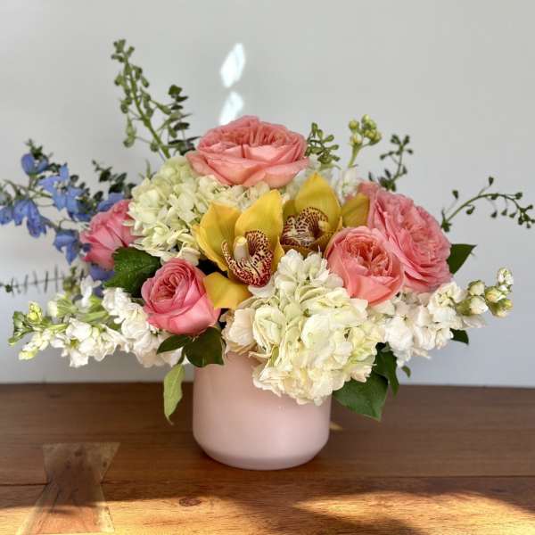 Pink roses and white hydrangeas in a blush vase with yellow orchids