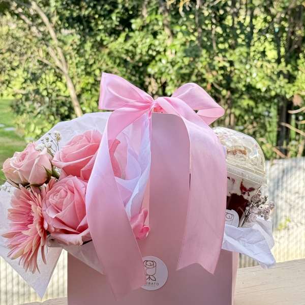 Pink rose bouquet in a gift box with a ribbon and a drink cup