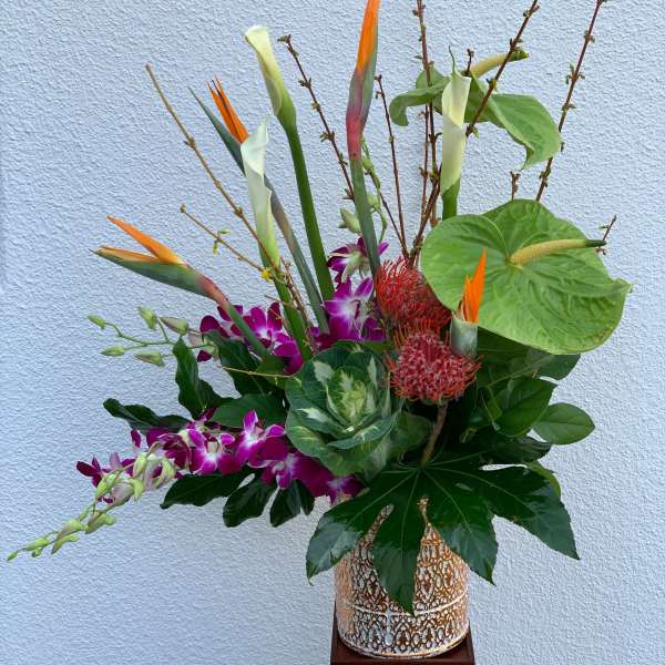 Tropical floral arrangement with orchids, bird of paradise, and anthurium in a decorative vase