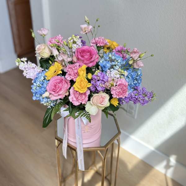 Colorful mixed bouquet in a pink hatbox on a gold stand
