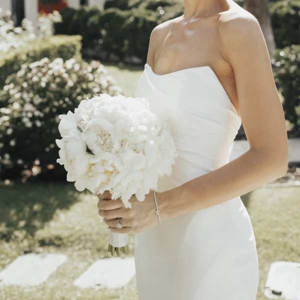 Bride holding a white bouquet in a strapless dress outdoors