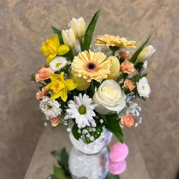Bouquet of yellow, white, and peach flowers in a white vase