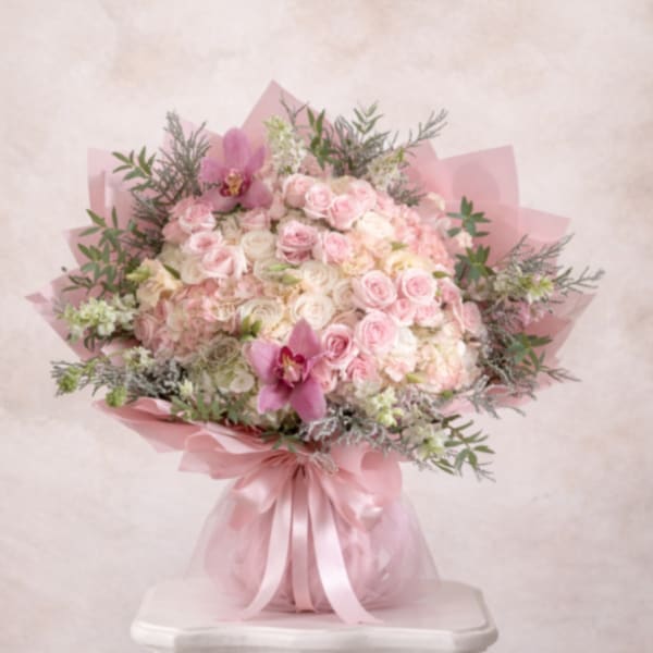 Large round bouquet of pale pink and white roses and hydrangeas with pink orchids, wrapped in pink paper and ribbon