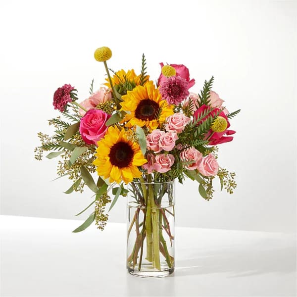 Bouquet of sunflowers and pink roses in a clear glass vase