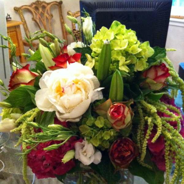 Mixed bouquet of roses, lilies, and hydrangeas in a glass vase