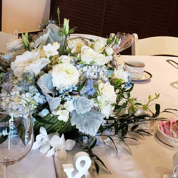 Low centerpiece of white and pale blue flowers on a table