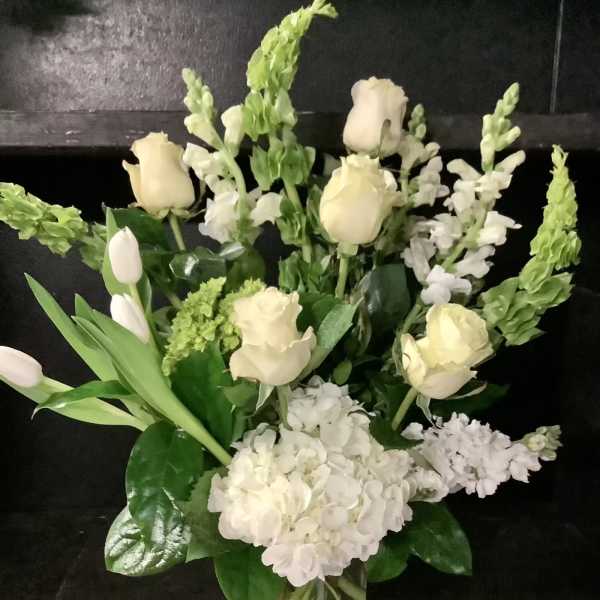 White roses and snapdragons arranged in a clear glass vase