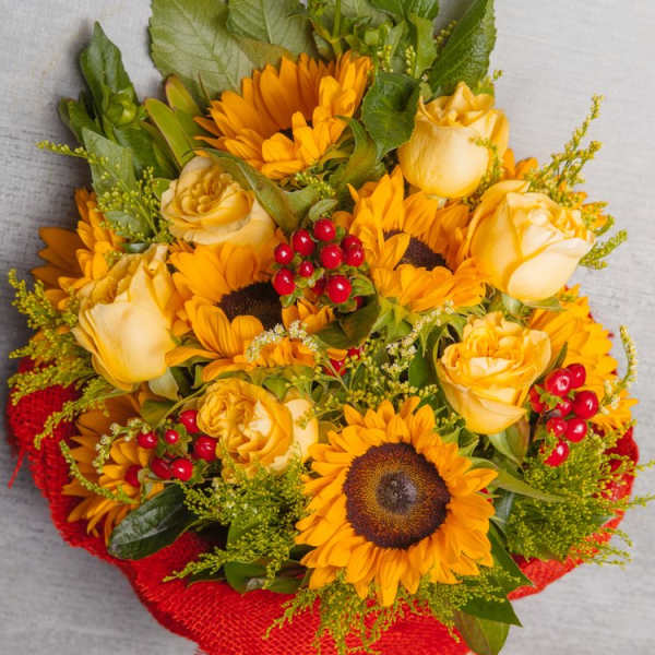 Bouquet of yellow roses and sunflowers wrapped in red paper