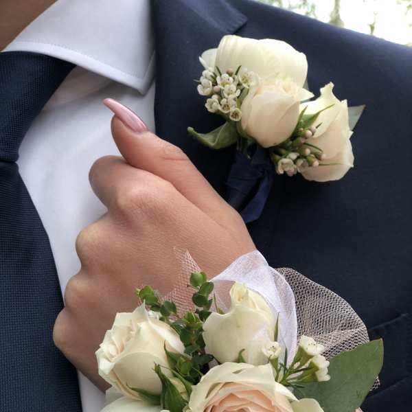 White rose boutonnieres and corsages on a navy suit and wrist