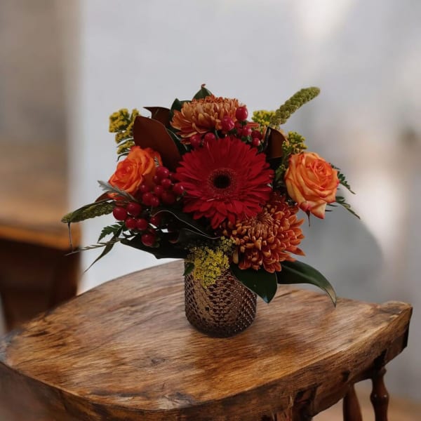 Bouquet of red and orange flowers in a textured vase