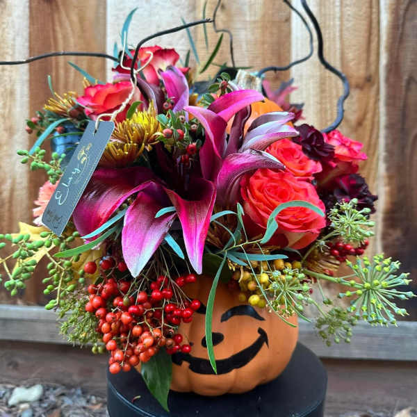 Halloween bouquet in a pumpkin container with pink and orange flowers