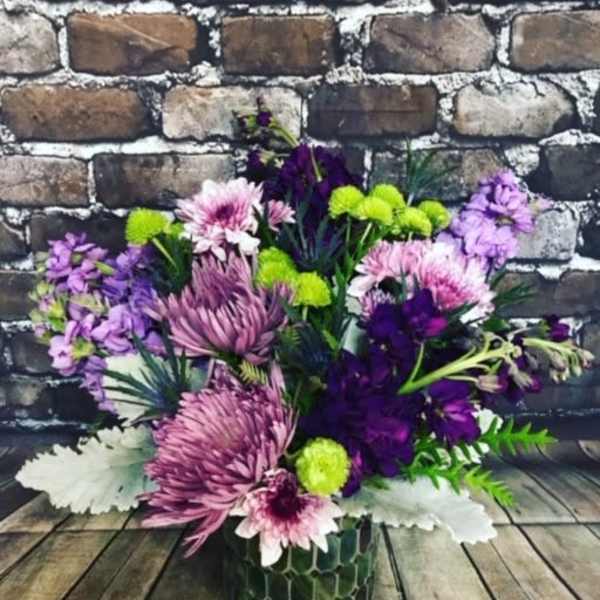 Purple and pink mixed bouquet in a green patterned vase