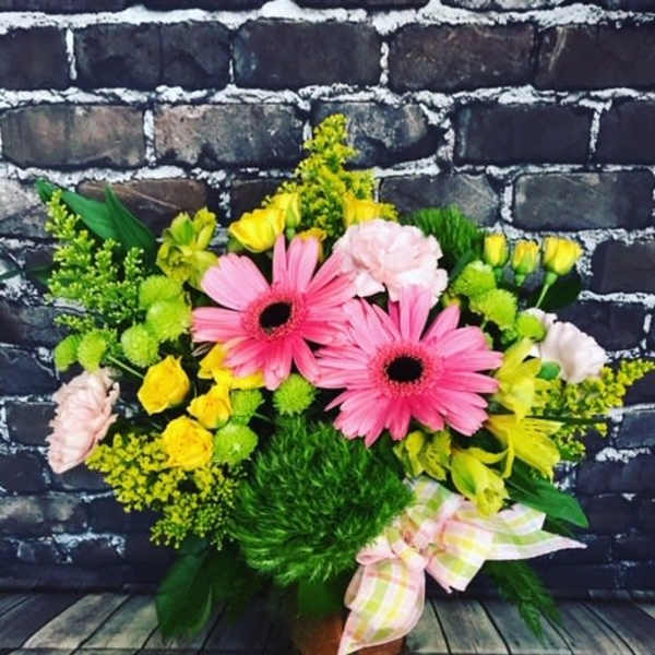 Bouquet of pink gerbera daisies and yellow flowers in a boot-shaped container
