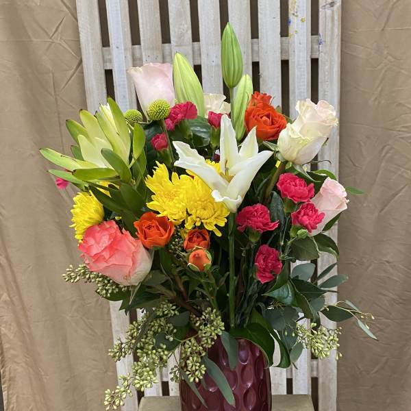 Mixed bouquet of roses, lilies, and chrysanthemums in a burgundy vase