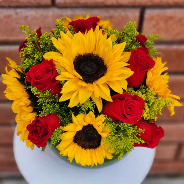 Bouquet of yellow sunflowers and red roses in a white vase