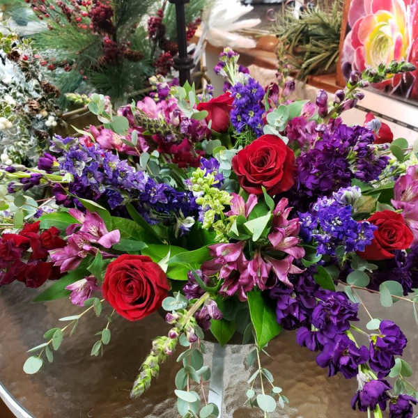 Bouquet of red roses and purple flowers in a glass vase