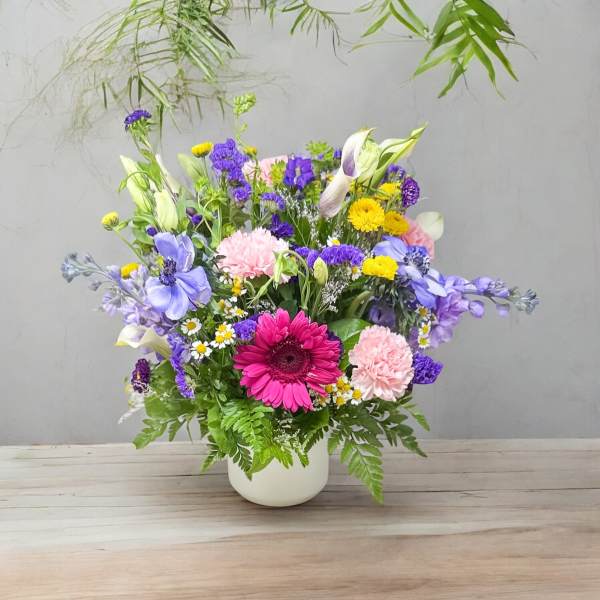 Mixed bouquet in a white vase with purple, pink, and yellow flowers